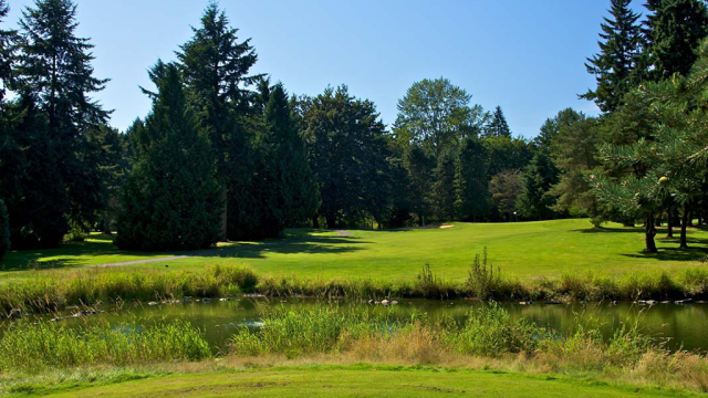 View of golf course fairway with pond and trees